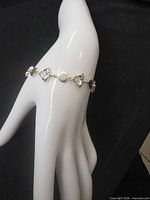 Bracelet displayed on mannequin hand showing heart link design and clasp