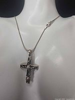 Necklace displayed on bust showing full view of cross pendant and chain