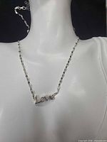 Necklace on display bust showing script pendant and chain