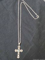 Full view of cross pendant necklace laid flat showing chain length and clasp