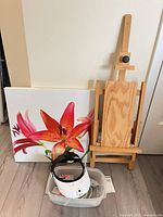 Group shot: easel, floral canvas, bin containing glue gun, glue sticks, headlamp