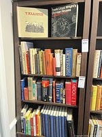 Overall view of three bookcase shelves showing variety of book spines and two featured titles on top