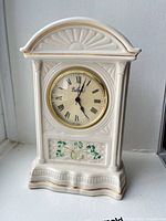 Front view of Belleek mantel clock showing dial, shamrock motif and overall design