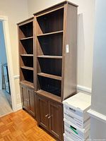 Two tall matching dark brown bookcases with lower cupboards