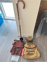 Group shot of compass, cane, leather satchel and CBC bag on floor