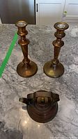 Top view of two copper candlesticks and copper teapot on countertop