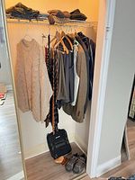 Overall view of hanging garments, hats on shelf, shoulder bag and shoes on floor
