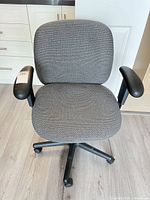 Front view of grey fabric office chair showing seat, backrest, arms and base
