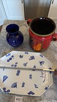 All three items together on countertop: red jar, cobalt vase, octagonal platter with measuring tape