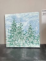 Front view of square canvas painting with snowy evergreens