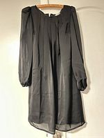 Front view of black pleated long-sleeve dress hanging