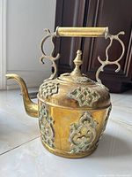 Full view of brass tea kettle showing ornate body, spout and handle