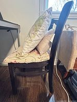 side view of wooden chair with floral seat cushion and pillows