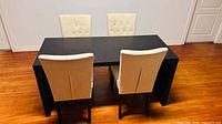 Top view showing black dining table with four cream chairs