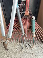 Group view of lopper, three-tine cultivator, red leaf rake and green-handled weeder
