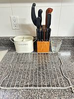 Overall view of knife block, cutlery holder, glass tumblers, metal rack on countertop