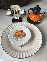 Group shot of platter, stack of six small plates, teapot, coffee cups on stand