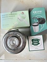 Overall lot showing pot bottom, food chopper box, car cup holder box, mug box