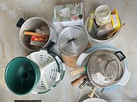 Top view of entire assortment including pots, funnel, colander, steamer, bowl, cutting board, boxed blender and utensils