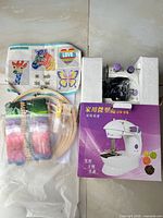 Sewing machine in box, cross-stitch threads, hoops and pattern sheets
