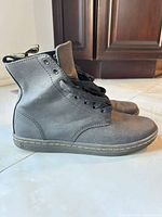 Side view of grey leather Dr. Martens ankle boots showing laces, yellow welt stitching and heel pull tab