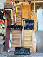 Full view of all three snow shovels leaning against wall