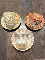 Three teacup and saucer sets displayed