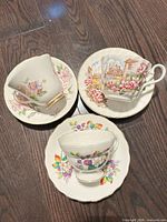 Top view of three teacup and saucer sets showing patterns and gold rims