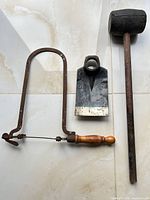 all three garden tools laid out: mallet, bow saw, hoe head
