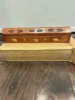Closed wooden incense burner with brass elephant inlays and leaf jali cutouts