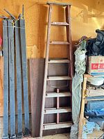 Full view of wooden ladder leaning against wall