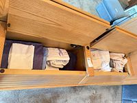 Open storage bench showing two compartments of folded linens and Cloudscape bag