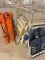Group shot of two orange bag chairs and four folded chairs leaning against wall