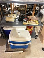 Shelf with two Igloo coolers, vintage plaid cooler, paddles and headcovers visible