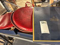 Two zipped red vinyl cushions inside blue Brooks Brothers box