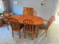 overview of dining table with six chairs and two leaves leaning against wall