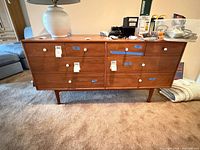 Front view of Drexel teak dresser showing eight drawers and white pulls
