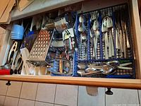 Open drawer showing full assortment of flatware and utensils
