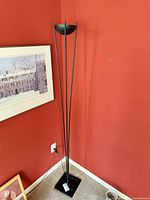 Full view of black metal torchiere floor lamp in corner