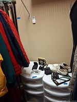 Closet corner showing plastic drawer units, golf shoes, gloves, rangefinder, hanging jackets