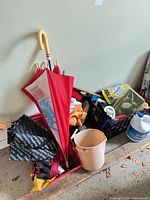 Overview of crate with umbrellas, bleach jug, pitcher and cleaning items