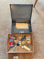 Open cash box on carpet, cardboard tray below with padlocks and keys