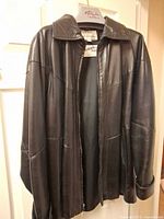 Front view of black leather jacket on hanger