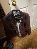 Full view of brown leather jacket on hanger