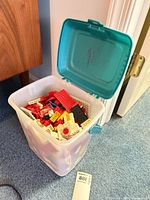 Bin open showing assorted red, white, yellow, blue bricks inside