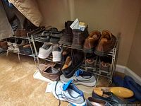 Multiple pairs of men’s shoes on and beside metal racks