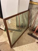 Front view of rectangular wood-framed mirror leaning against wall