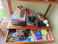 Overall view of top shelf and open drawer showing light, letter tray, cables box and assorted supplies
