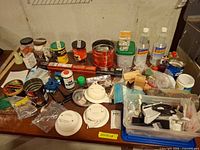 Overall view of assorted hardware, smoke detectors, caulk, tins and plastic bin