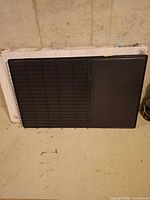 Folded black wire crate with plastic tray leaning against wall